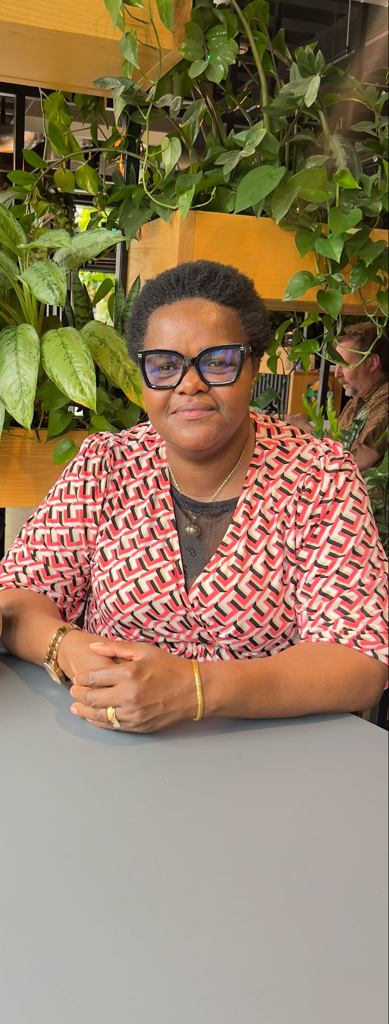 The designer sitting at a table with plants in the background